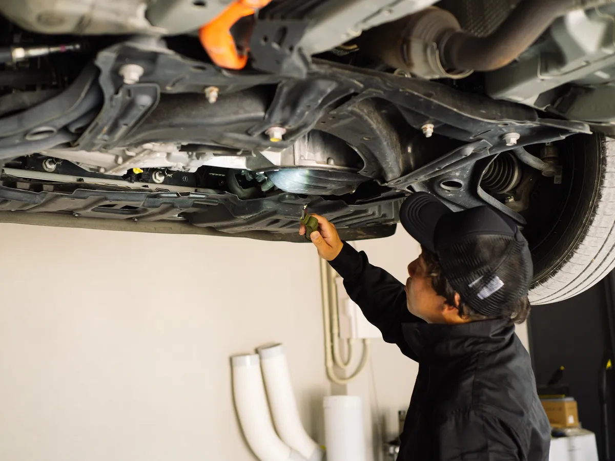 リフトで上げた車の下回りを整備する職人