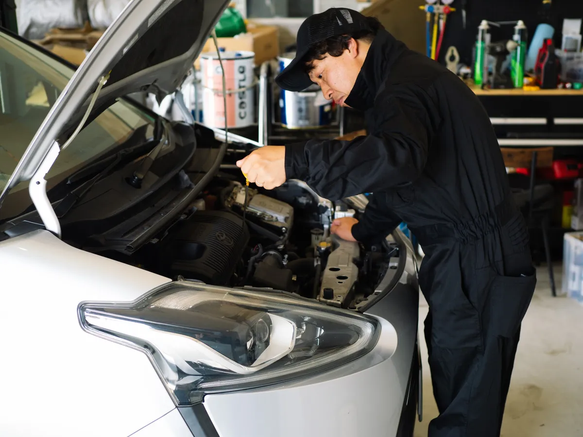 ボンネットを開けて整備するパンダ自動車の職人